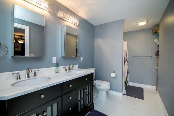 a bathroom with a double vanity sink toilet and mirror