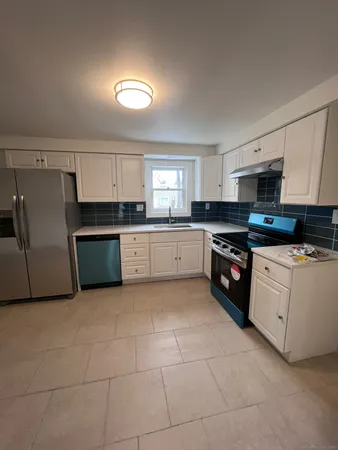 a large kitchen with granite countertop a stove a sink dishwasher and a refrigerator