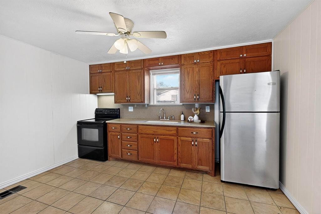 507 North Rusk Street Weatherford, TX 76086 - Photo 10 of 35 a kitchen with stainless steel appliances granite countertop a refrigerator a sink and a stove