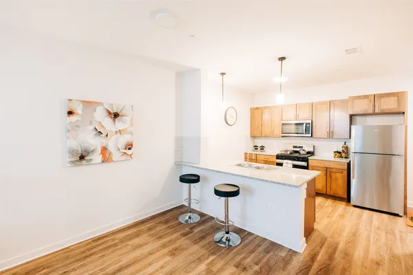 a kitchen with a refrigerator a stove top oven a counter space and wooden floor