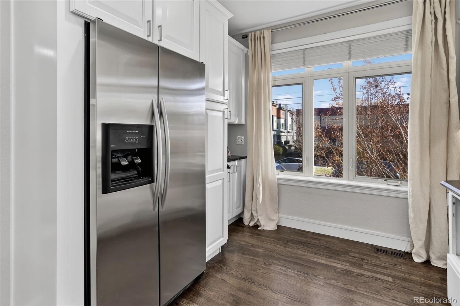 2311 Decatur Street Denver, CO 80211 - Photo 10 of 31 a view of a refrigerator in kitchen and an empty room with wooden floor mirror