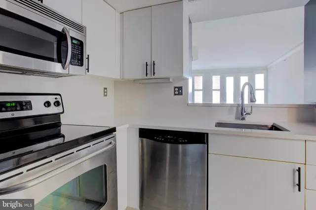 a kitchen with stainless steel appliances white cabinets and a stove top oven