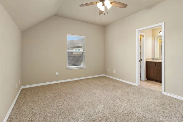 an empty room with a chandelier fan and windows