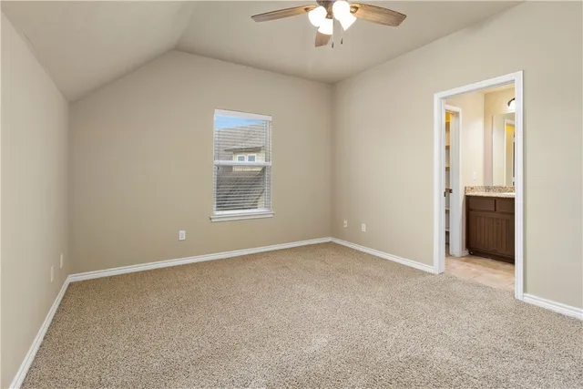 an empty room with a chandelier fan and windows