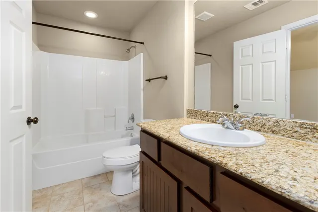 a bathroom with a granite countertop sink a toilet a mirror and shower
