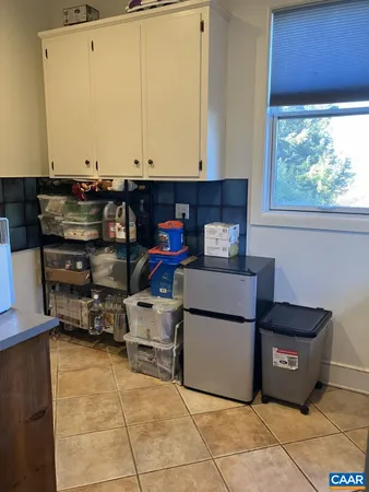 a living room with furniture and a refrigerator