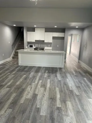 a large kitchen with stainless steel appliances wooden floors and view living room