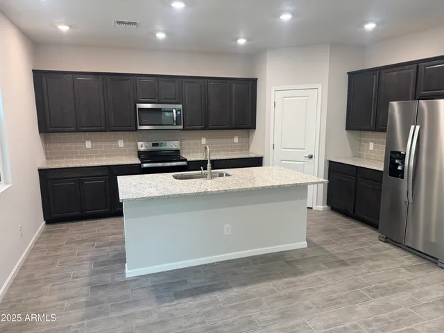 a large kitchen with stainless steel appliances a sink and a refrigerator