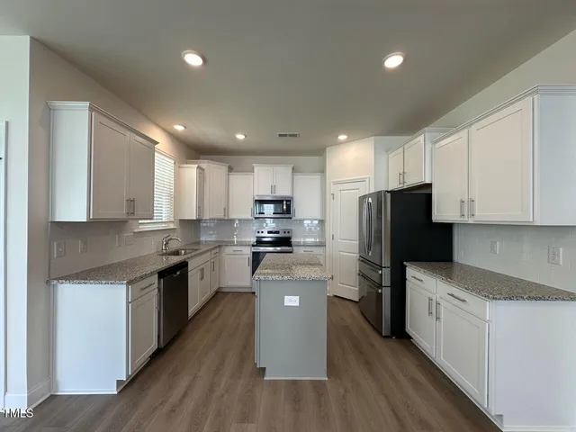 a kitchen with a refrigerator a sink dishwasher and a stove top oven with wooden floor