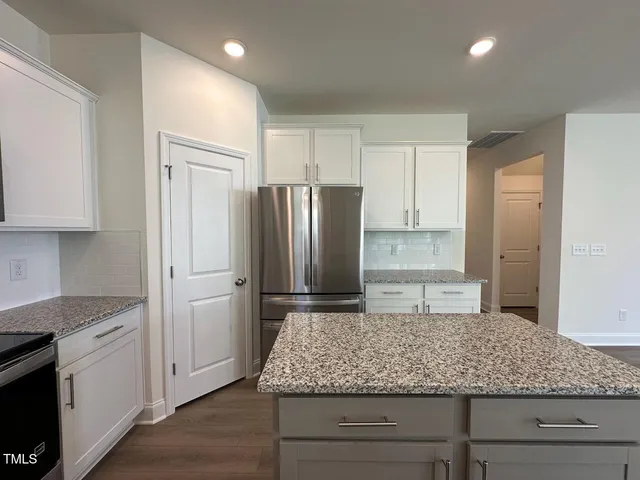 a kitchen with kitchen island granite countertop cabinets and stainless steel appliances
