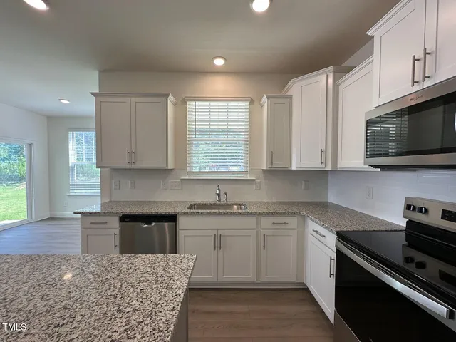 a kitchen with stainless steel appliances granite countertop a sink dishwasher stove and microwave with wooden cabinets