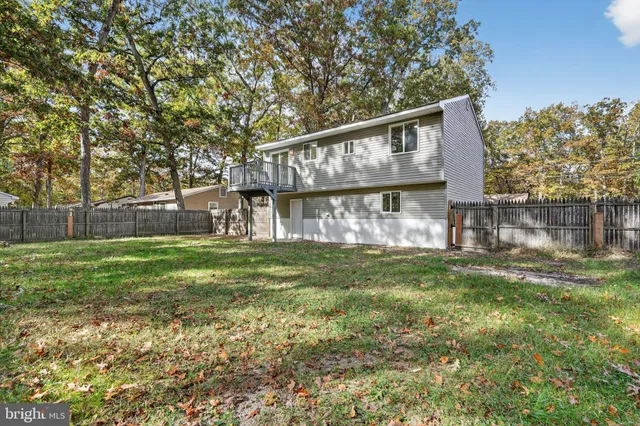 a view of backyard with wooden fence and large trees