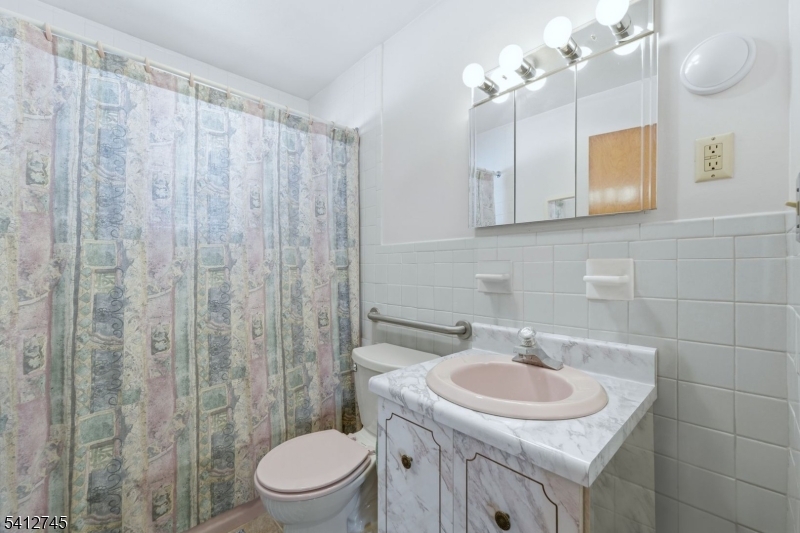 47 Clinton Avenue New Providence, NJ 07974 - Photo 26 of 43 a bathroom with a sink a toilet and shower curtain