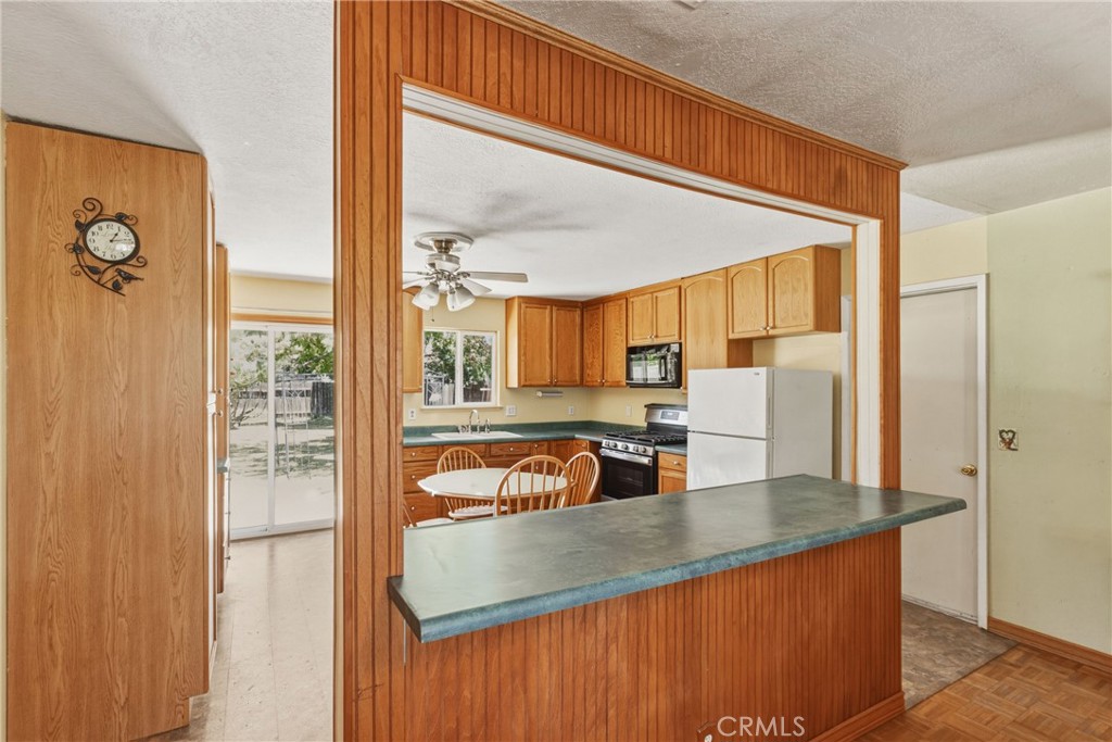 6812 Helton Street Winton, CA 95388 - Photo 7 of 24 a kitchen with stainless steel appliances granite countertop a refrigerator a stove and a sink with wooden floor