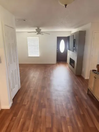 a view of empty room with wooden floor and fan
