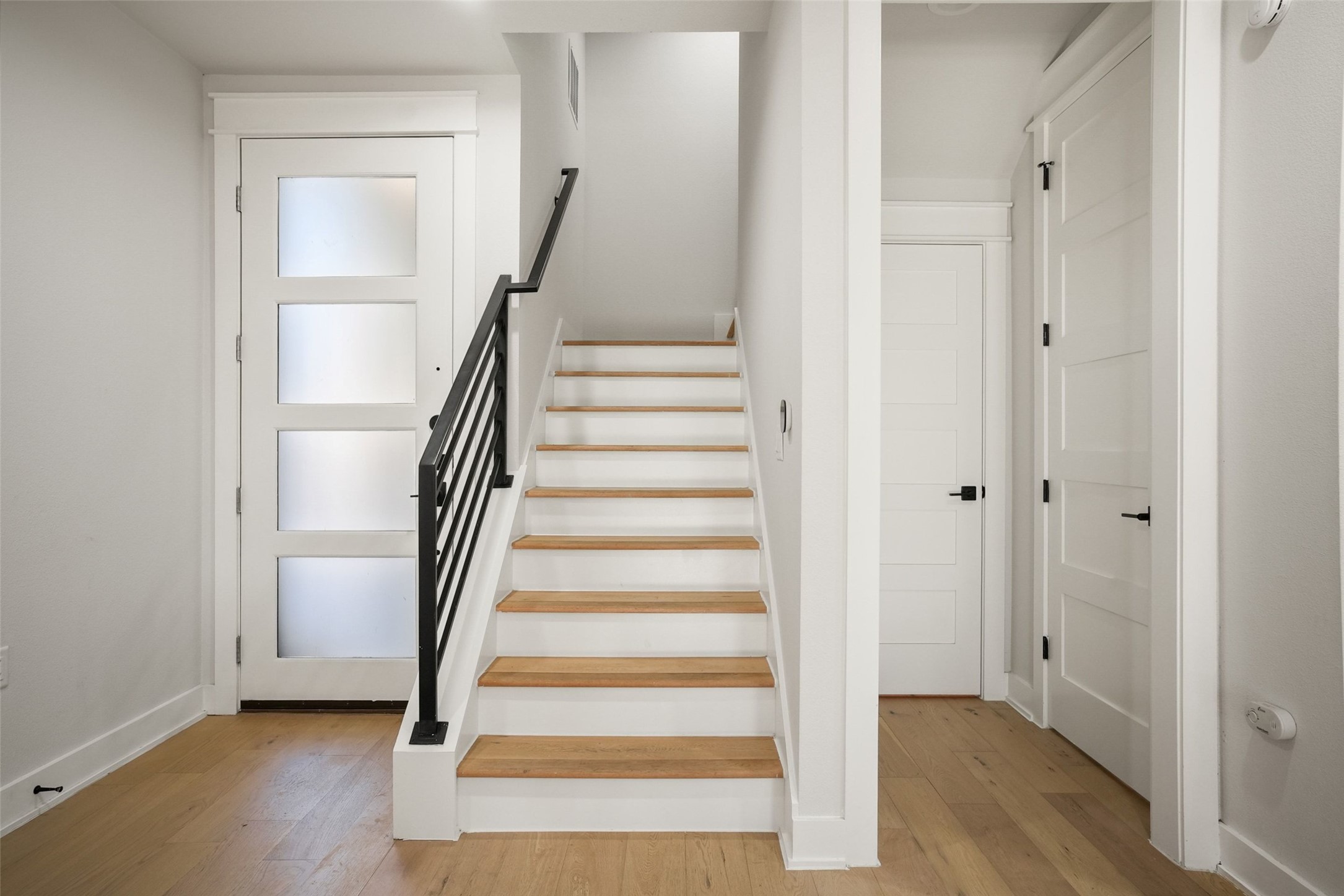 5109 Stone Gate Drive, Unit 2 Austin, TX 78721 - Photo 24 of 36 Staircase featuring wood-finish treads, white risers, and a contemporary black metal railing