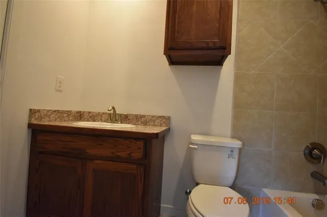 a bathroom with a granite countertop toilet and a sink