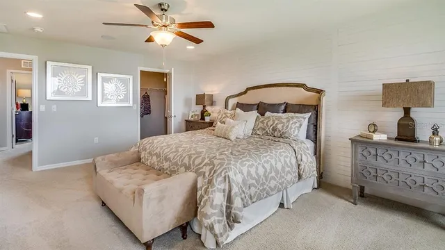 a bedroom with a bed a ceiling fan and a dresser