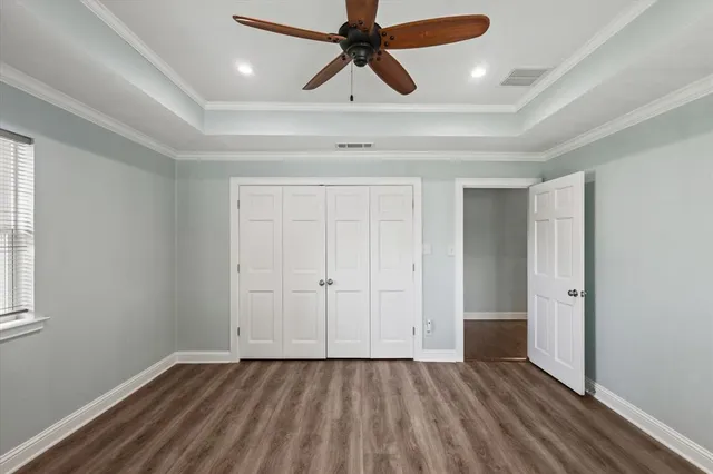 an empty room with wooden floor ceiling fan and windows