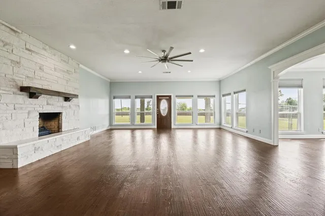 an empty room with fireplace wooden floor and windows