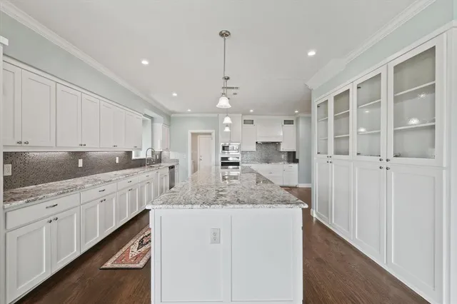 a kitchen with stainless steel appliances granite countertop a refrigerator a sink and wooden floors