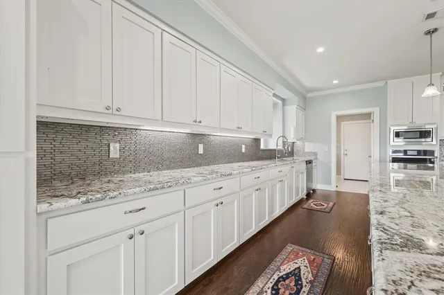 a kitchen with granite countertop white cabinets and stainless steel appliances
