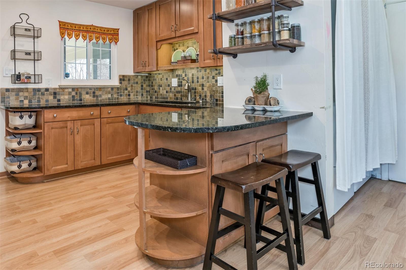3435 Ward Road Wheat Ridge, CO 80033 - Photo 14 of 32 a kitchen with granite countertop a table chairs stove and cabinets
