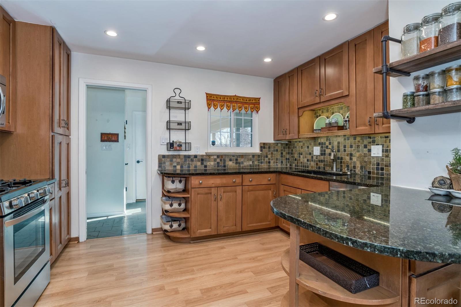 3435 Ward Road Wheat Ridge, CO 80033 - Photo 9 of 32 a kitchen with stainless steel appliances granite countertop a stove a sink and a microwave