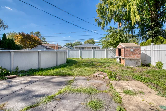 a backyard of a house with plants and large trees