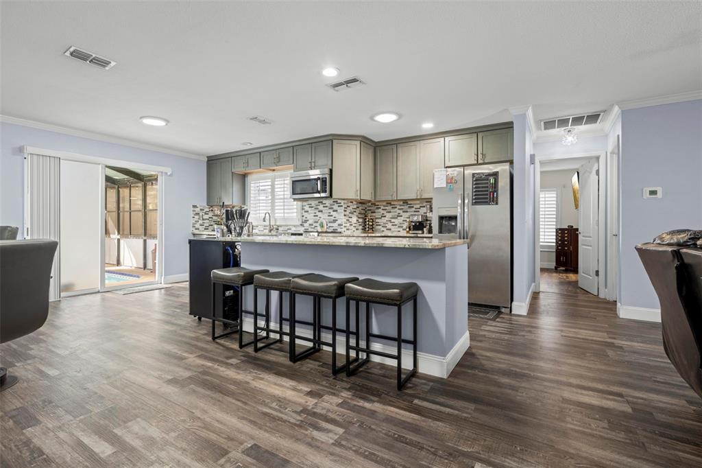 2399 Gallagher Avenue Spring Hill, FL 34606 - Photo 30 of 56 a kitchen with stainless steel appliances granite countertop a stove a refrigerator a sink a dining table and chairs with wooden floor