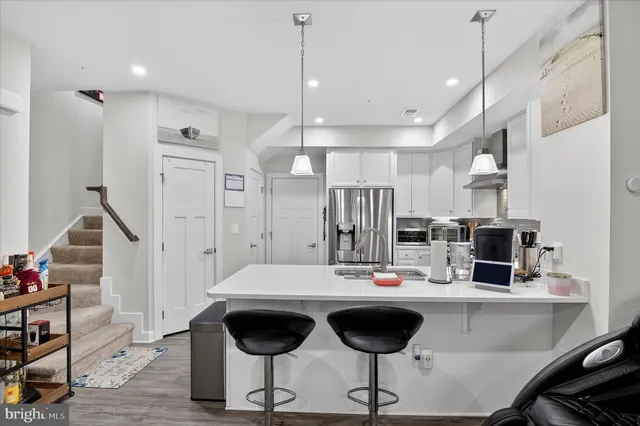 a kitchen with stainless steel appliances kitchen island granite countertop a table chairs and a refrigerator