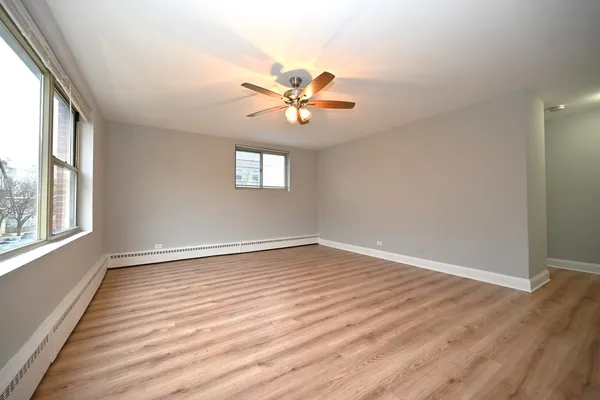 a view of an empty room with window and wooden floor