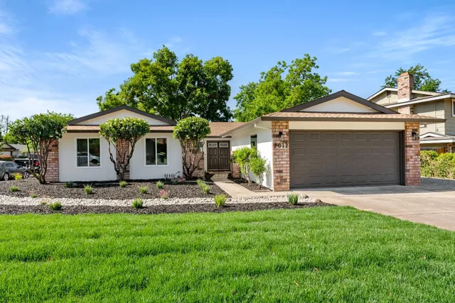 a front view of a house with a garden and plants