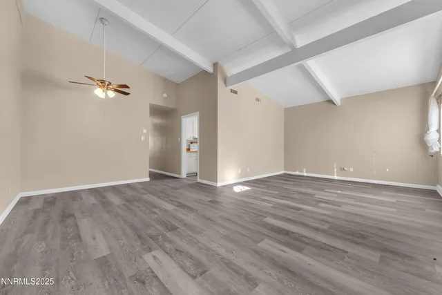 an empty room with wooden floor and a ceiling fan