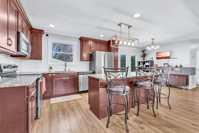 a kitchen with stainless steel appliances wooden floor and large windows