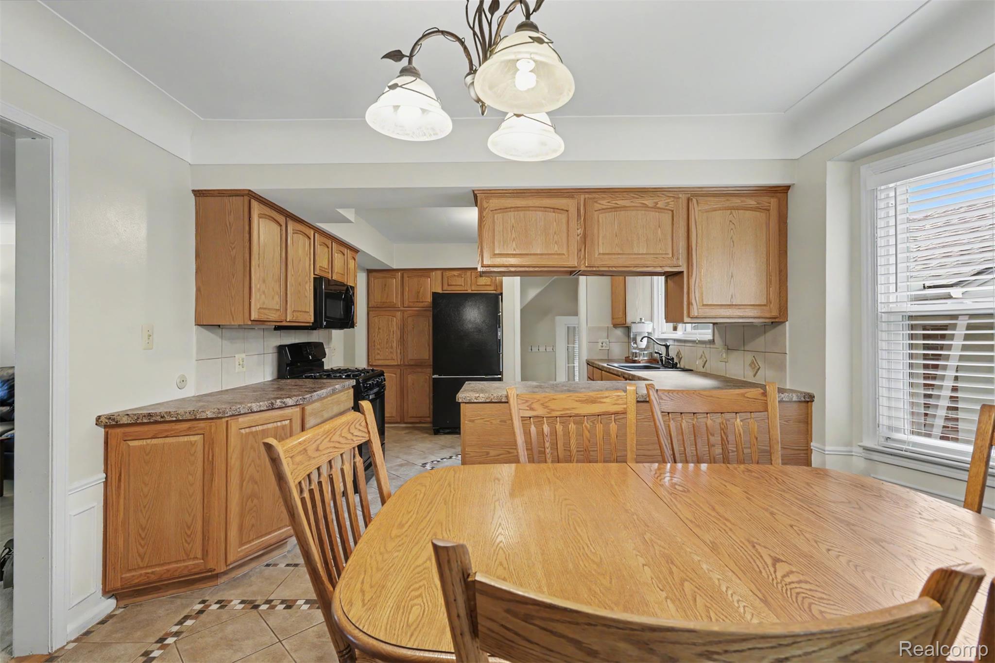 7136 Rosedale Boulevard Allen Park, MI 48101 - Photo 12 of 51 Kitchen featuring wood-finish cabinetry, solid surface countertops, tile flooring, and integrated black appliances