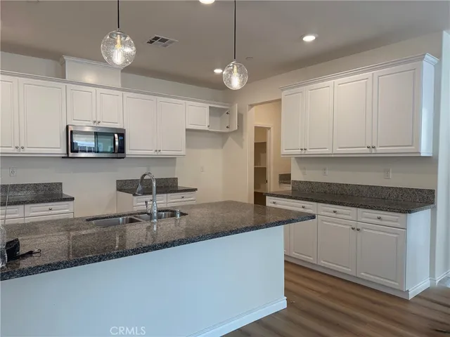 a kitchen with kitchen island granite countertop a sink a center island a counter space and cabinets