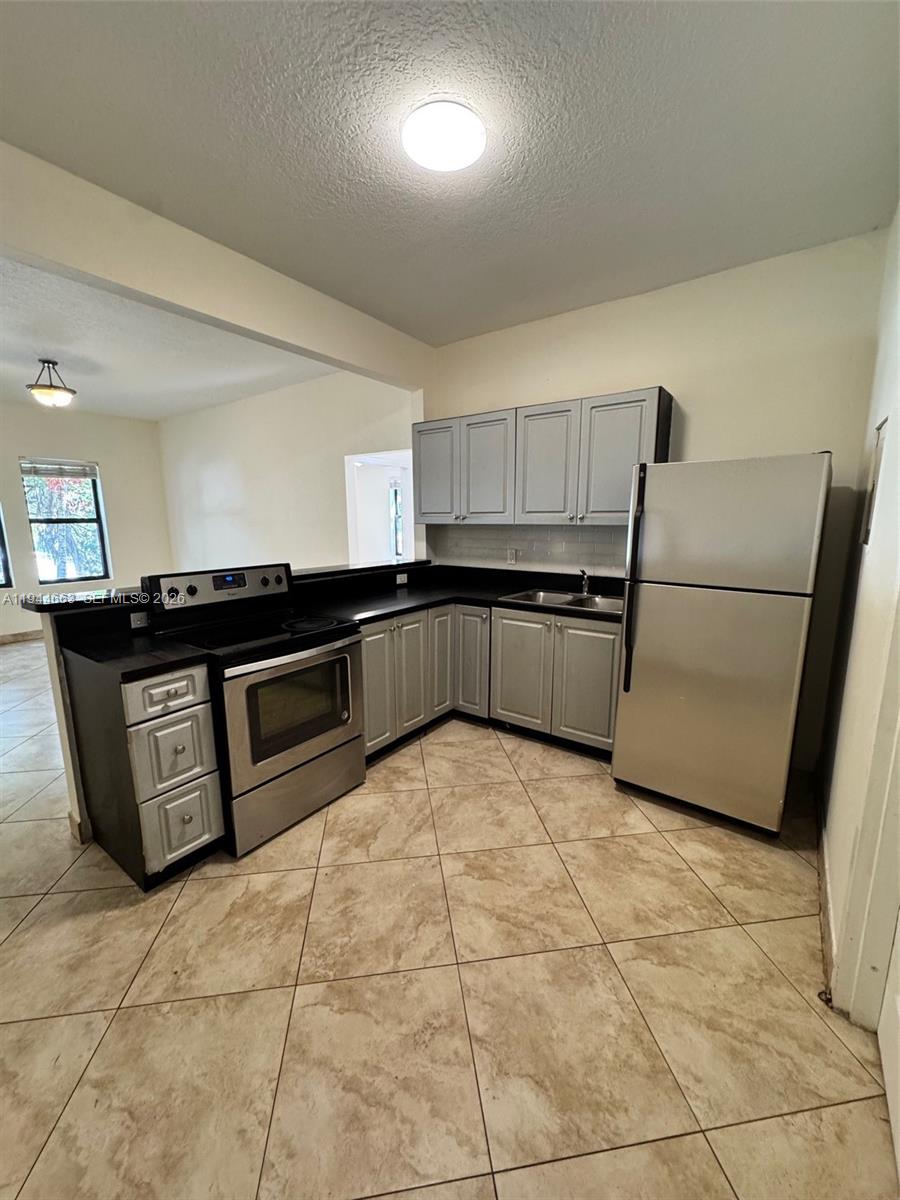 2000 Monroe Street, Unit 11 Hollywood, FL 33020 - Photo 5 of 22 a kitchen with granite countertop a refrigerator and a stove top oven
