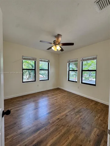 an empty room with windows and ceiling fan