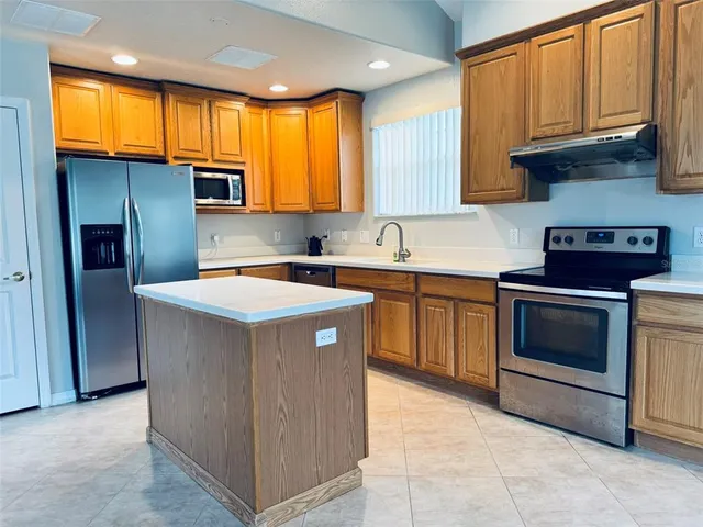 a kitchen with stainless steel appliances granite countertop a stove a sink dishwasher a refrigerator and a microwave