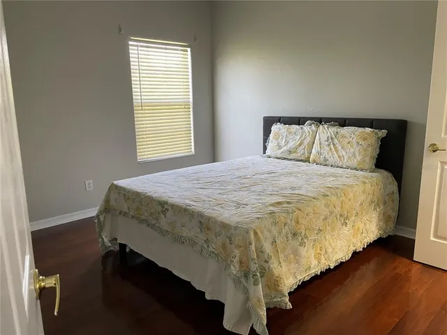 a bed sitting in a bedroom next to a window with wooden floor