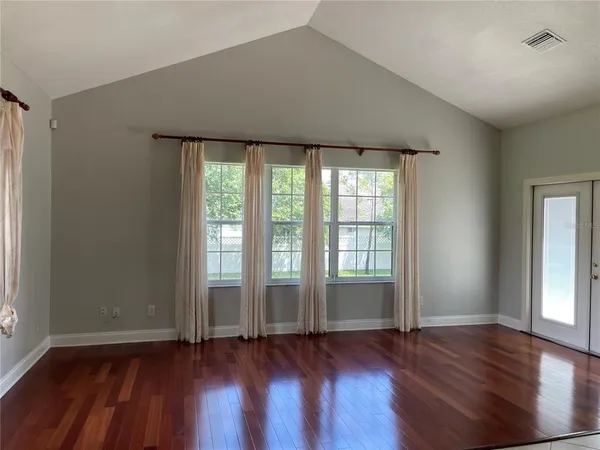 an empty room with wooden floor and windows