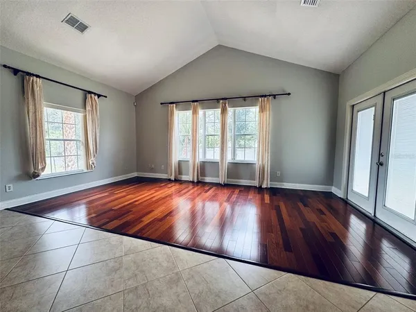 an empty room with wooden floor and windows