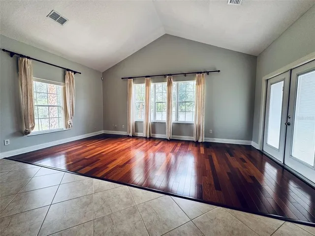 an empty room with wooden floor and windows
