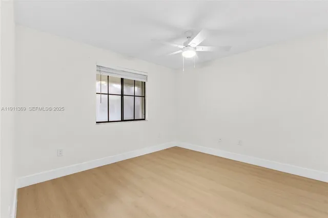 an empty room with a window and ceiling fan