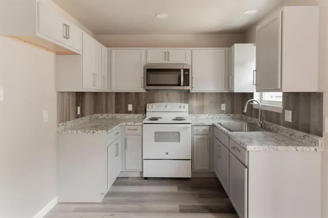 a kitchen with granite countertop white cabinets and white appliances