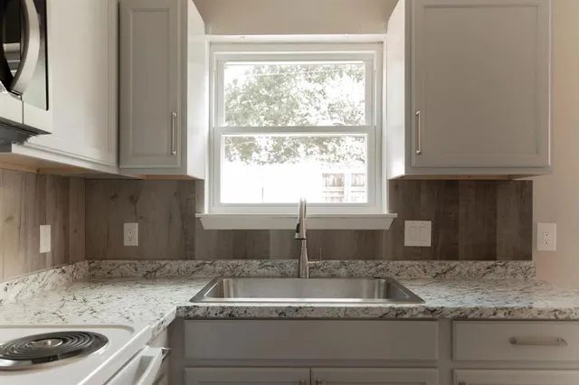 a kitchen with granite countertop a sink a stove and microwave