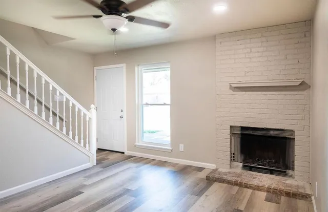 an empty room with wooden floor a fireplace and windows