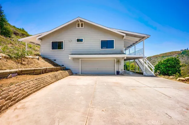 a front view of house along with road and trees