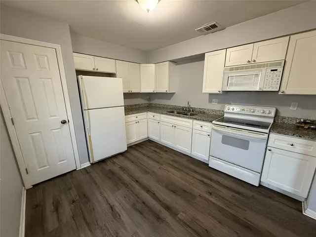 a kitchen with white cabinets white stainless steel appliances and sink